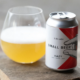 Can of Small Beer hazy craft beer beside a glass on a wooden table.